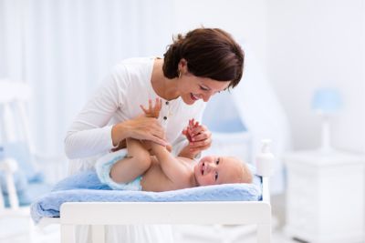 Maman chnageant le lange de son bébé par un plus écologique.